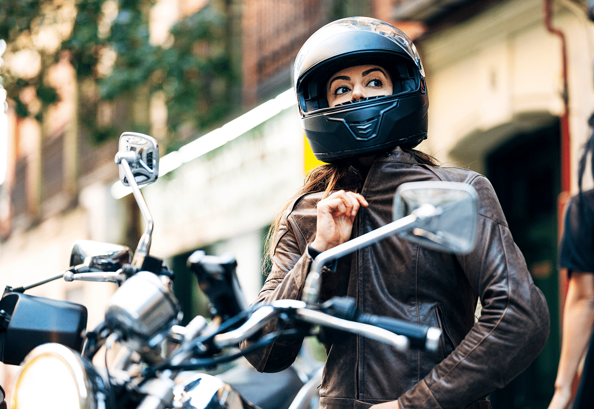 Seguro de moto Chica montada en una moto, cerrando la cremallera de su chaqueta