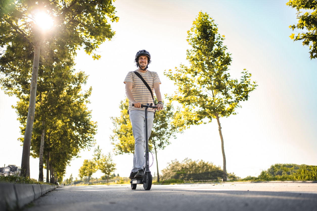 E-scooter Hombre con casco protector mientras monta su e-scooter