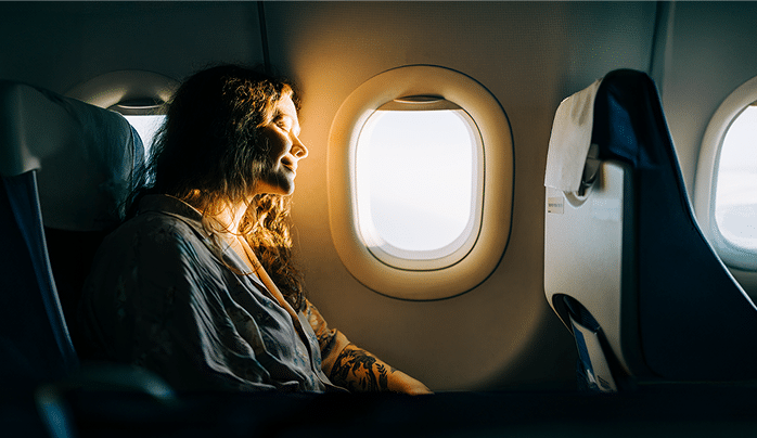 Serene female passenger enjoying sunny view from airplane window