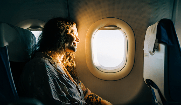 Multiviajes Serene female passenger enjoying sunny view from airplane window