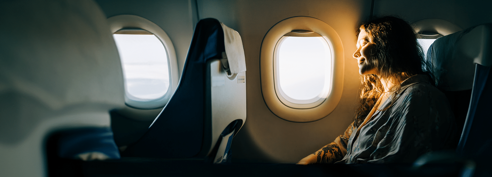 Multiviajess Serene female passenger enjoying sunny view from airplane window
