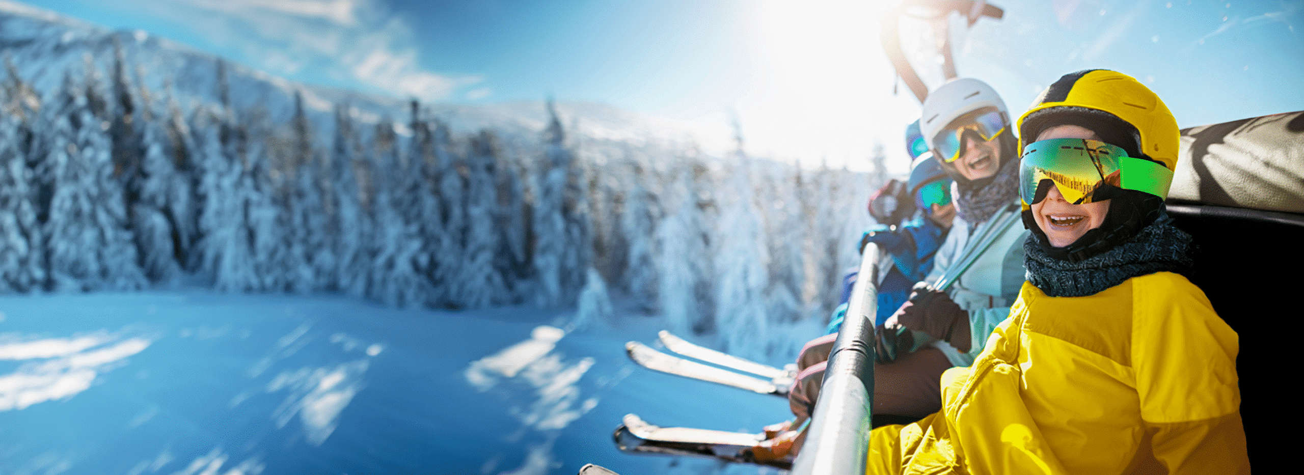 Seguro de esqui Familia sonriendo en el telesilla de una pista de esquí
